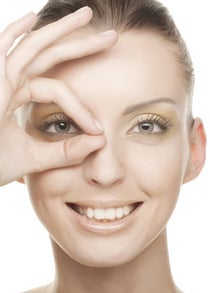 Woman smiling and circling here eye with her thumb and index finger