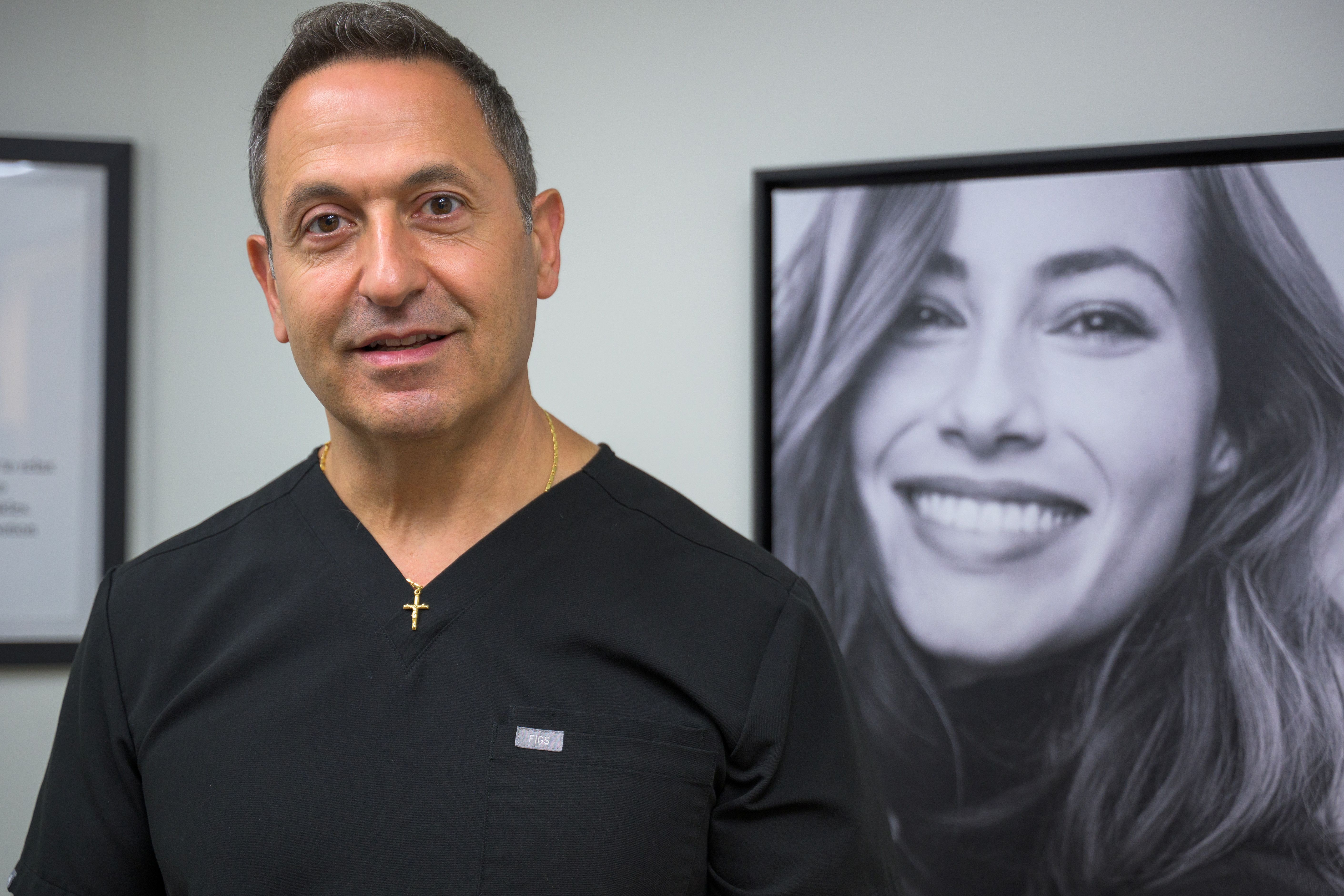 Dr. Merheb behind him is a photo of a smiling woman
